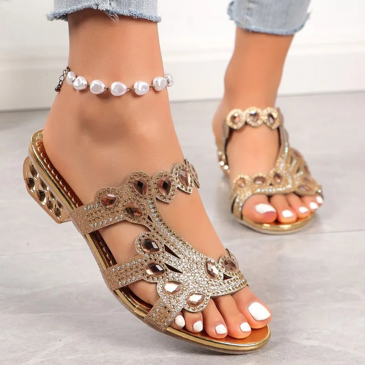 Model feet wearing stylish glamour sandals on a plain background.
