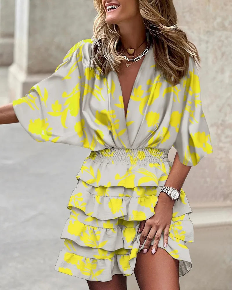Female wearing a colorful printed ruffle mini dress against a plain background.