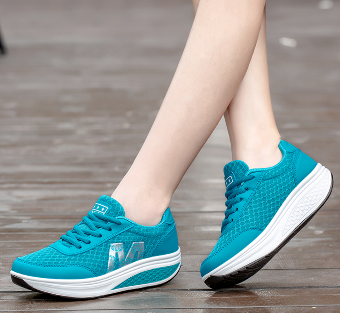 Woman showing everyday walking sneakers with a clean plain backdrop.