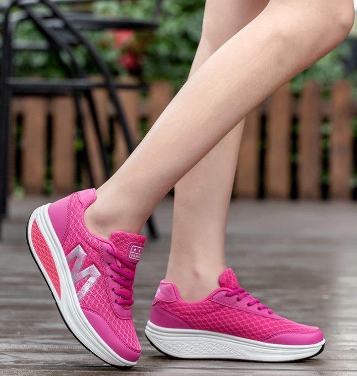Female feet wearing cushioned walking sneakers on a plain background.