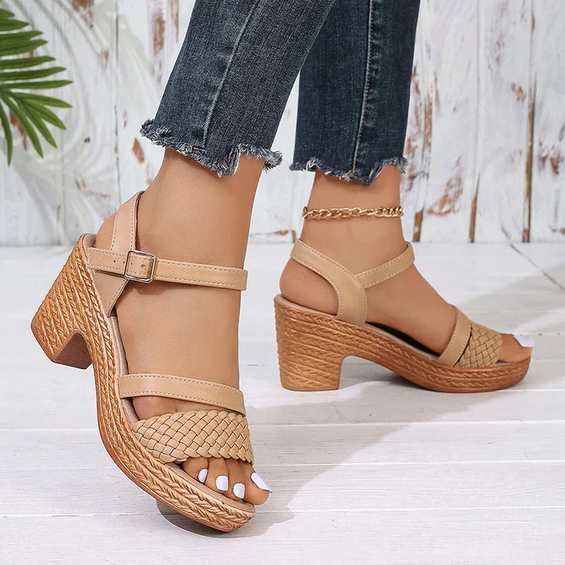 Model showing ankle strap woven platform sandals on feet with plain background.