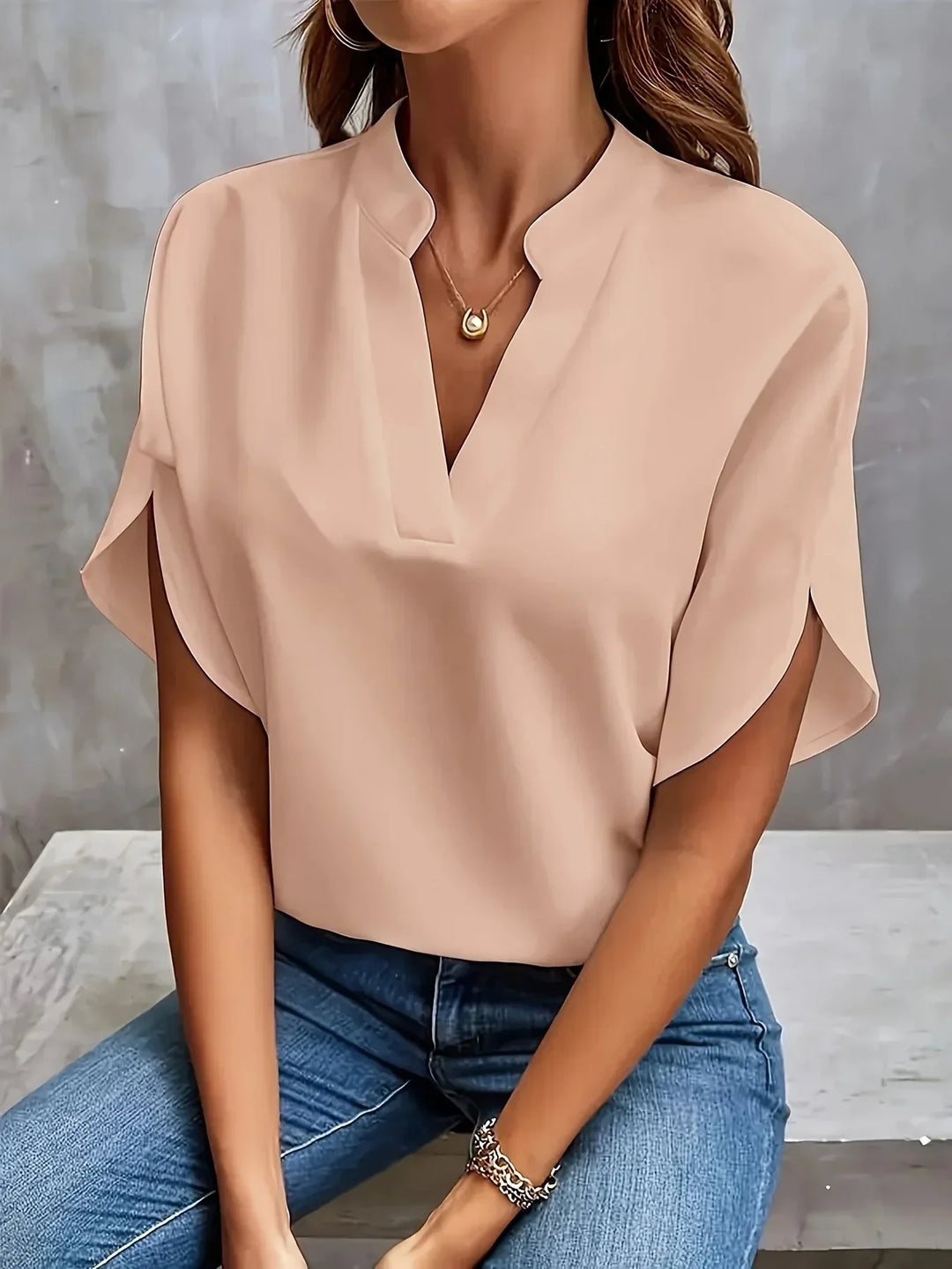 Minimalist blouse styled with a model on a clean background emphasizing shoulder definition.