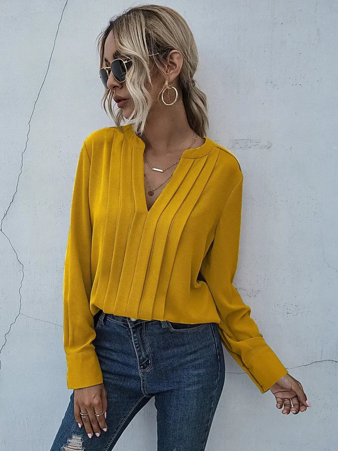 Refined women’s blouse with soft pleats shown on a person against a clean background.