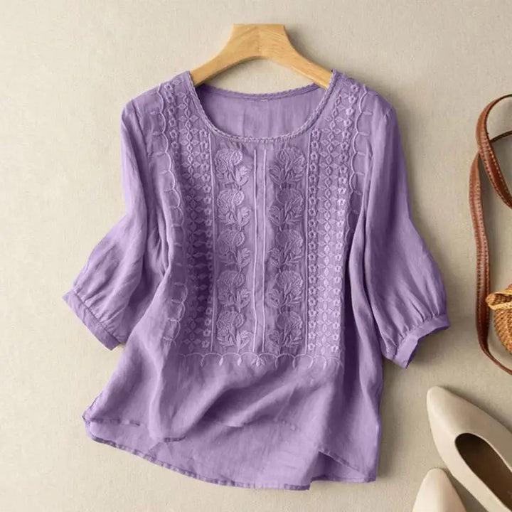 Airy women’s blouse with elegant embroidery against plain background.