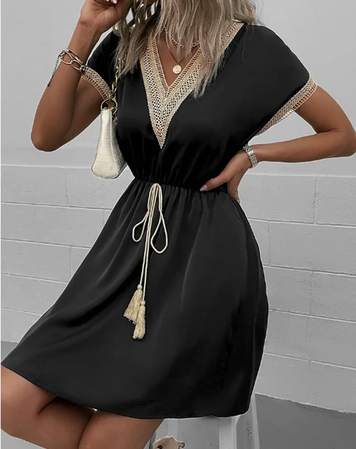 Short sleeve boho dress on a plain background featuring a waist-defining tie and soft drape.