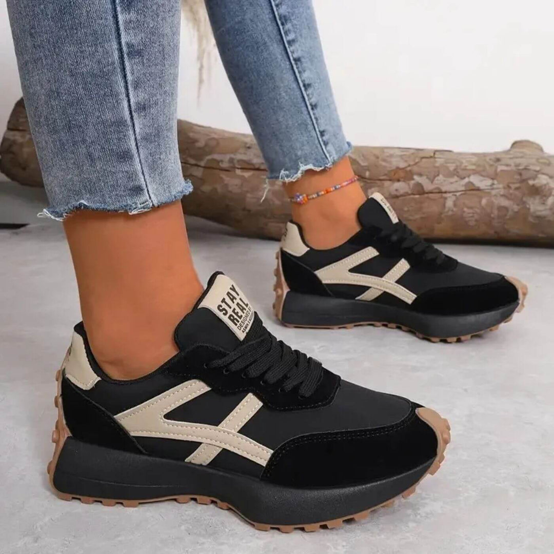 Female model wearing cushioned walking sneakers on a plain background.