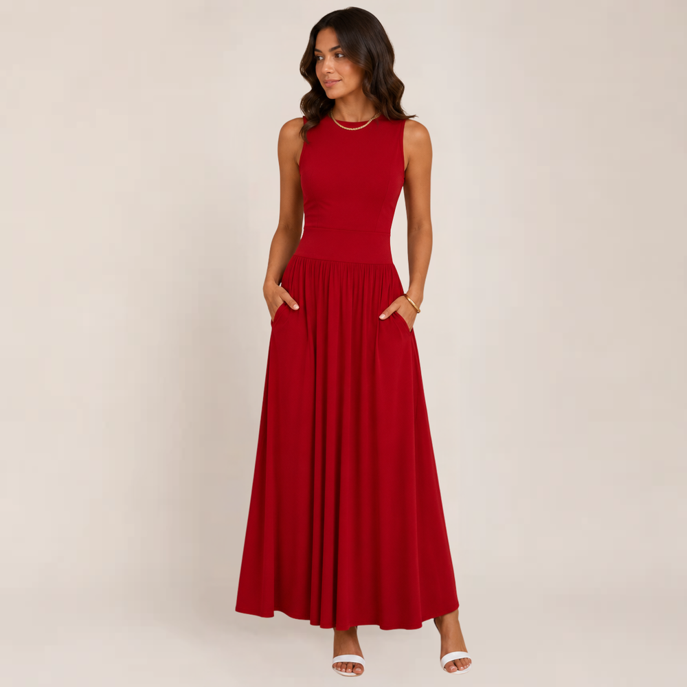 Woman posing in a flowing sleeveless formal maxi dress against a plain background.
