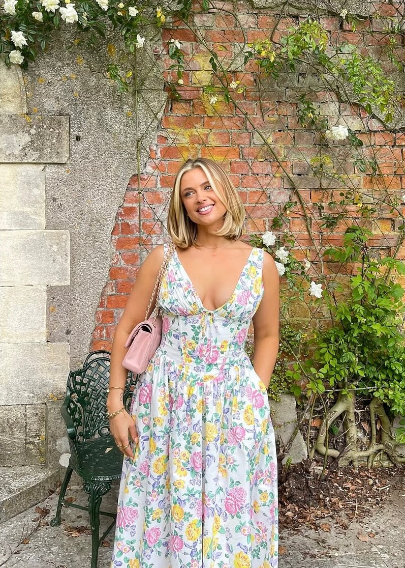 Female model in a relaxed summer dress on a stone brick background.