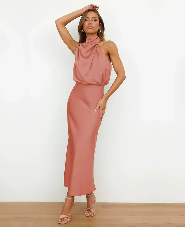 Female model styled in a midi length dress on a plain backdrop.