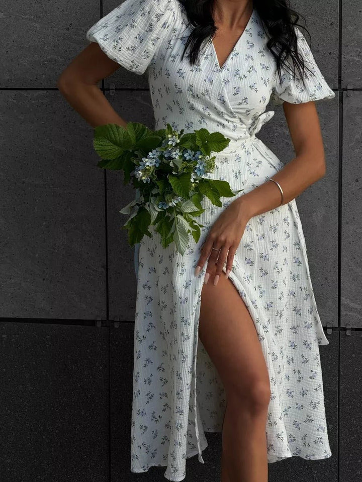  Woman in a floral midi dress featuring a flattering waist detail on a plain background.