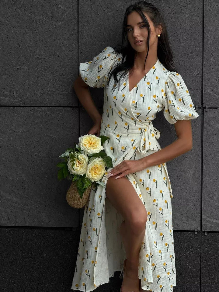 Female wearing a floral midi wrap dress with a side slit on a plain background.