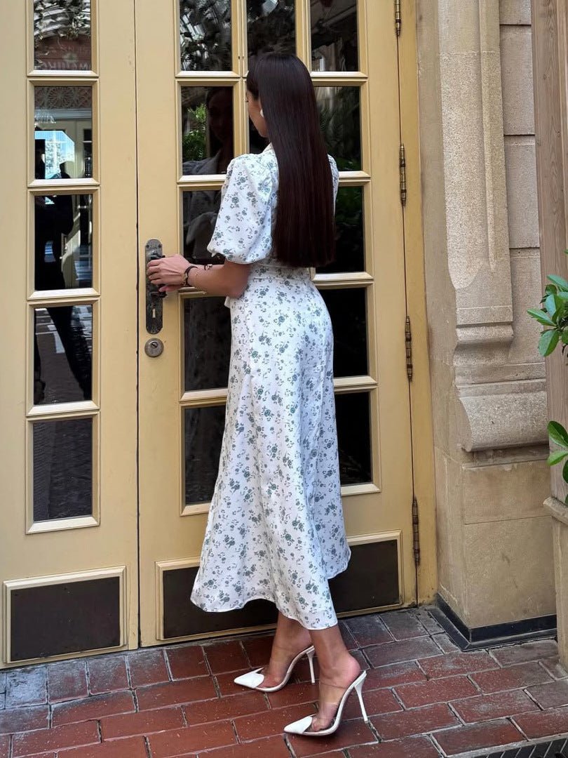  Female model in a floral print midi dress with a belted waist and soft drape on a plain background.
