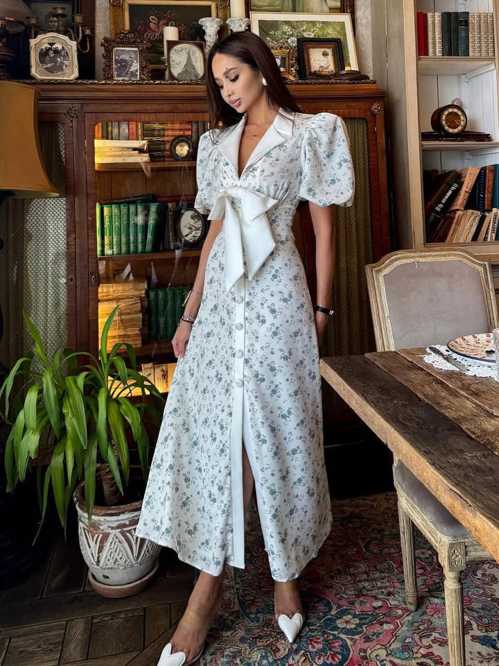  Woman showcasing a flowing floral midi dress with a feminine silhouette on a plain background.