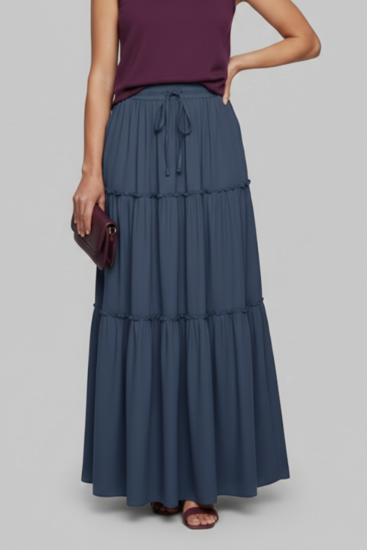 Model standing tiered blue skirt gray background full length