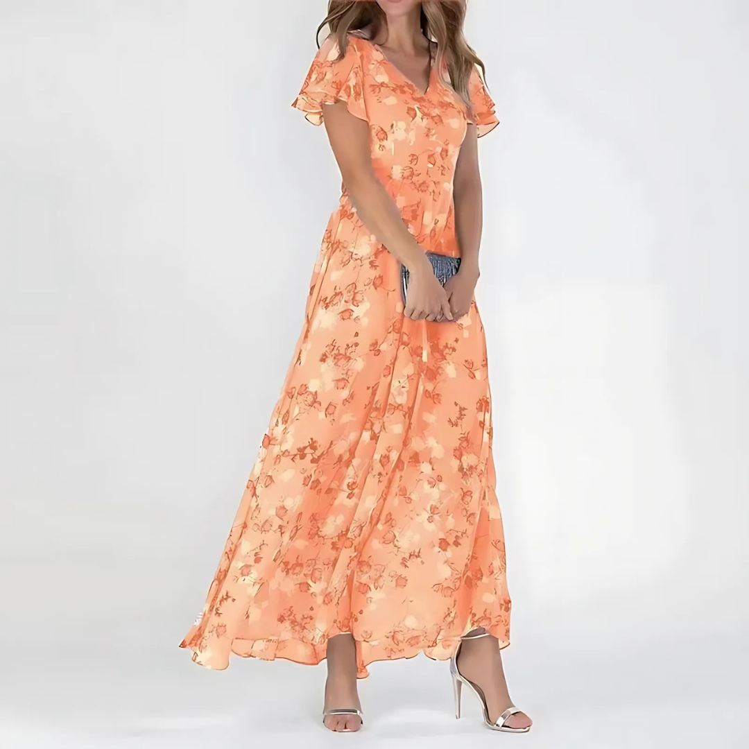 Woman wearing a floral flowy dress on a plain background.
