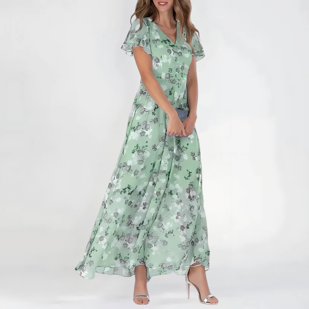 Female wearing a flowy floral dress with soft styling on a plain background.