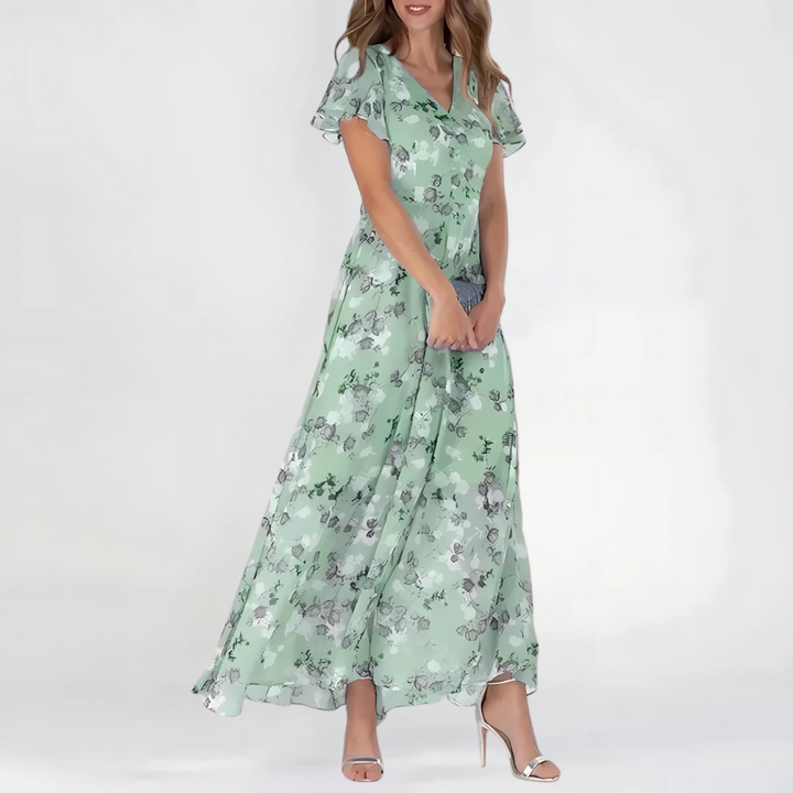 Female wearing a flowy floral dress with soft styling on a plain background.