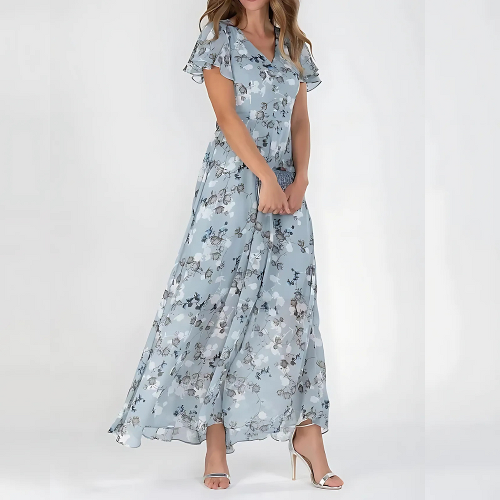 Female model in a floral dress with a relaxed silhouette on a plain background.