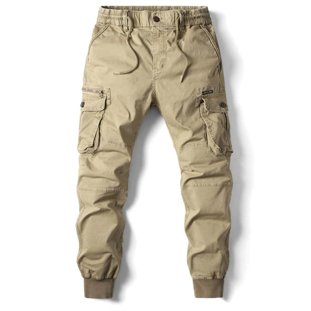  Man showcasing modern cargo pants with utility pockets on a plain background.