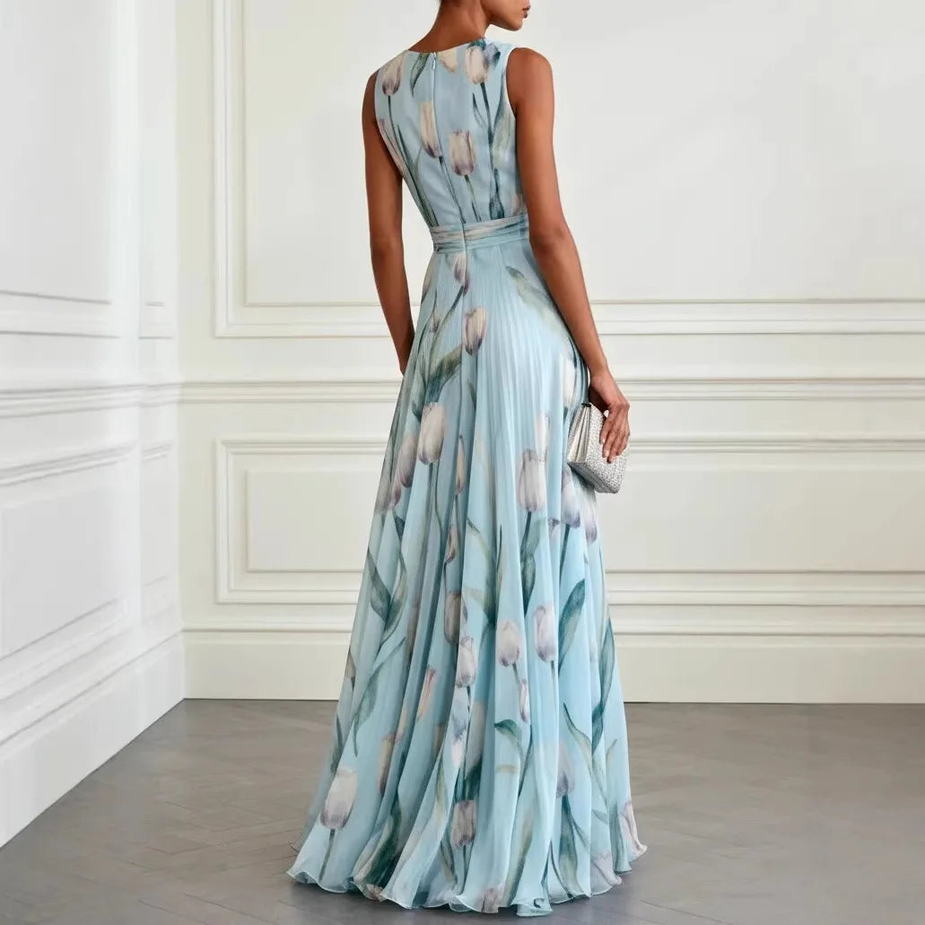 Woman posing in a flowing floral wrap dress against a plain background.