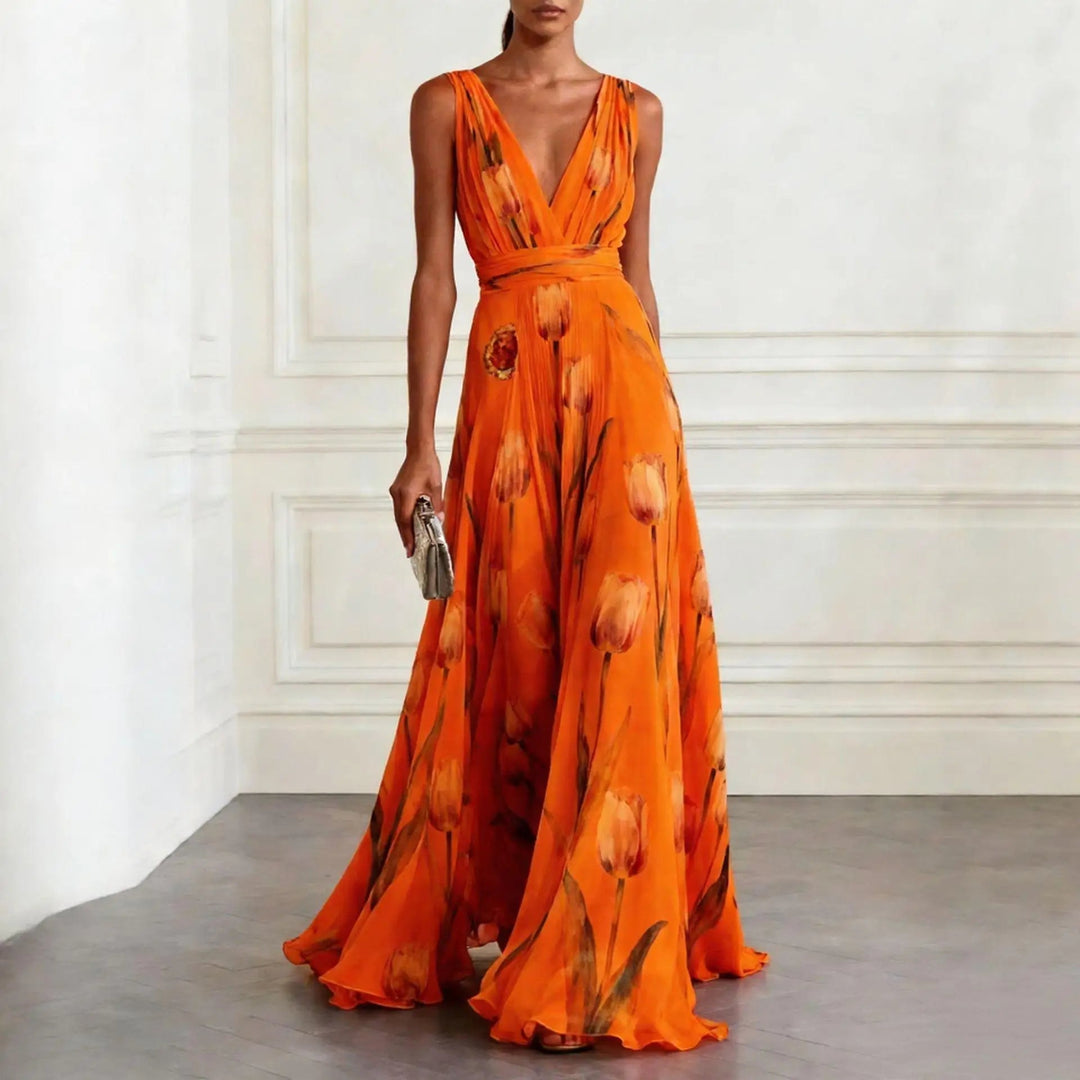 Woman in a floor-length tulip print dress with soft layered fabric on a plain background.