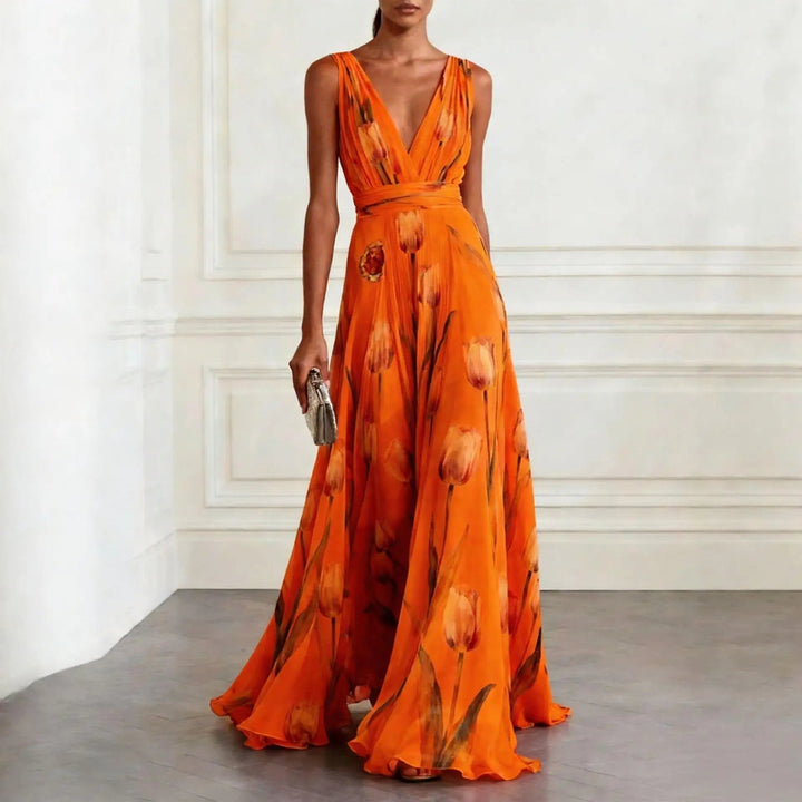 Woman in a floor-length tulip print dress with soft layered fabric on a plain background.