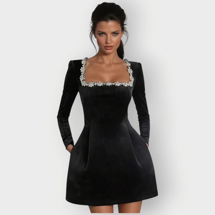 Female model wearing a velvet mini dress with a square neckline against a plain background.