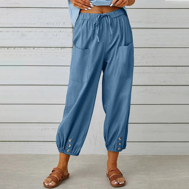 Female model wearing flowing high waist trousers on a clean background.