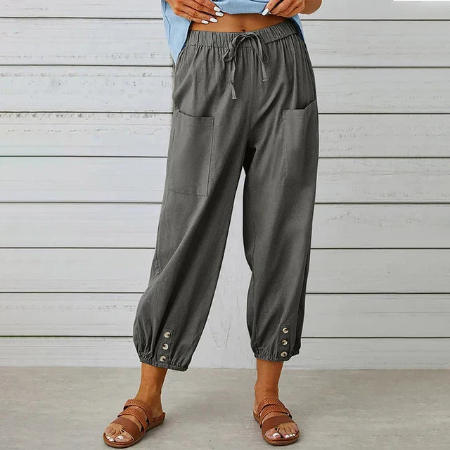 Woman showcasing relaxed fit pants with a high waist on a plain background.