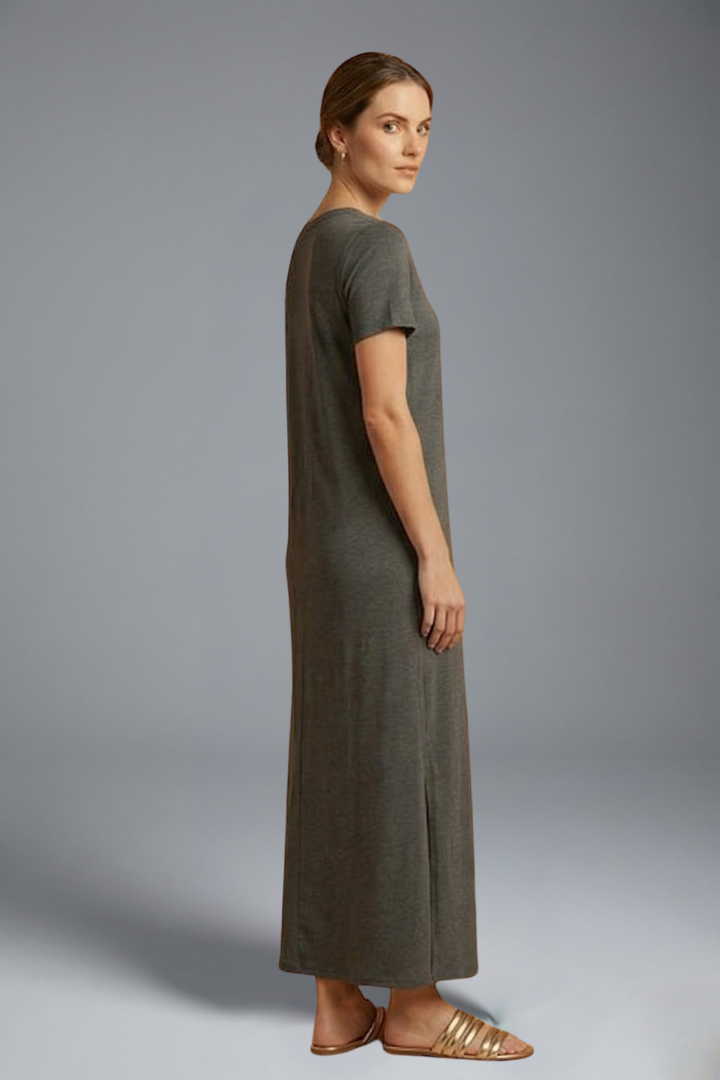 Model standing sideway in relaxed full-length dress