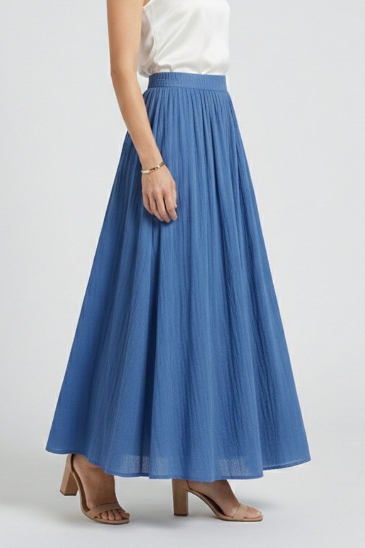 Model in flowing blue skirt full length gray background
