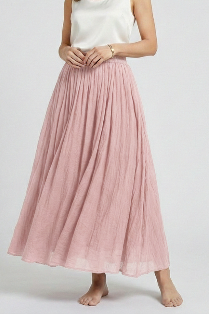 Model posing in long pink skirt gray backdrop