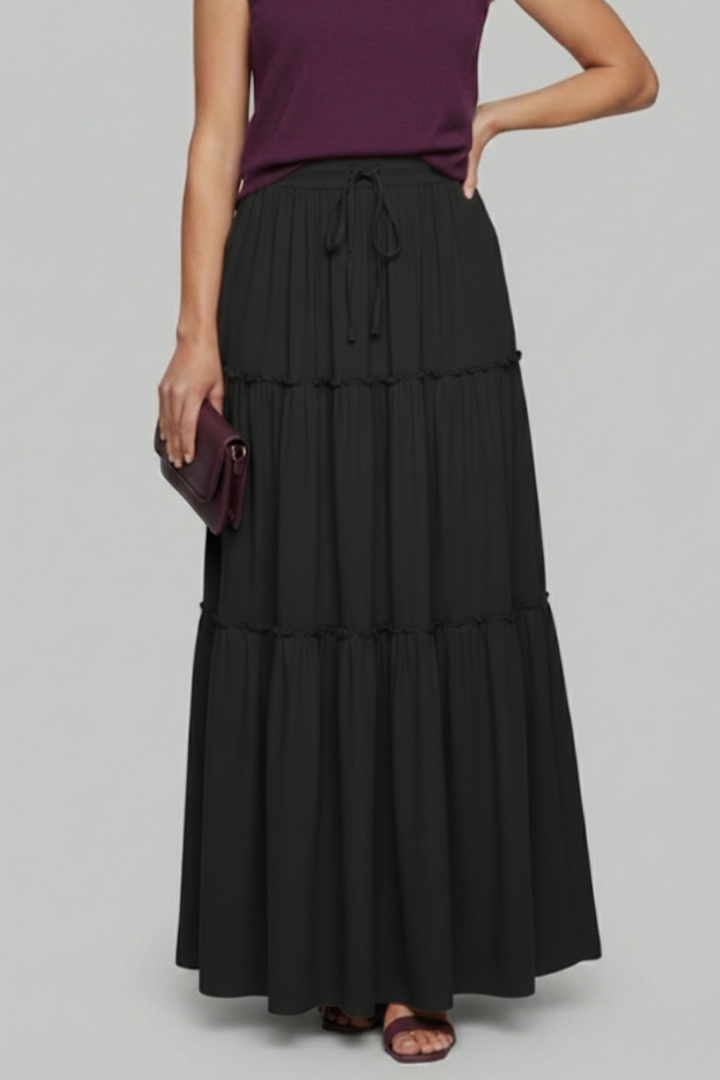 Model standing wearing long black skirt gray background shot
