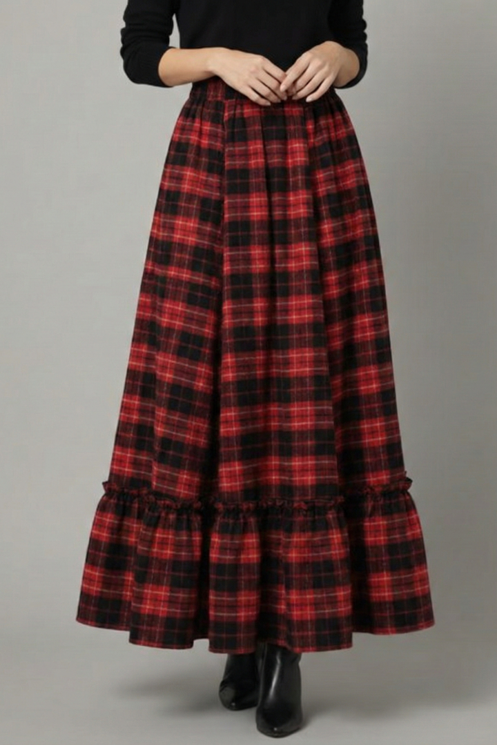 Model standing in flowy red and black skirt gray background