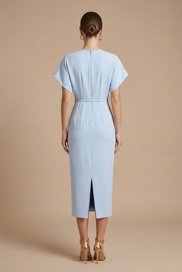 Woman wearing a belted midi dress with flowing batwing sleeves on a plain background.