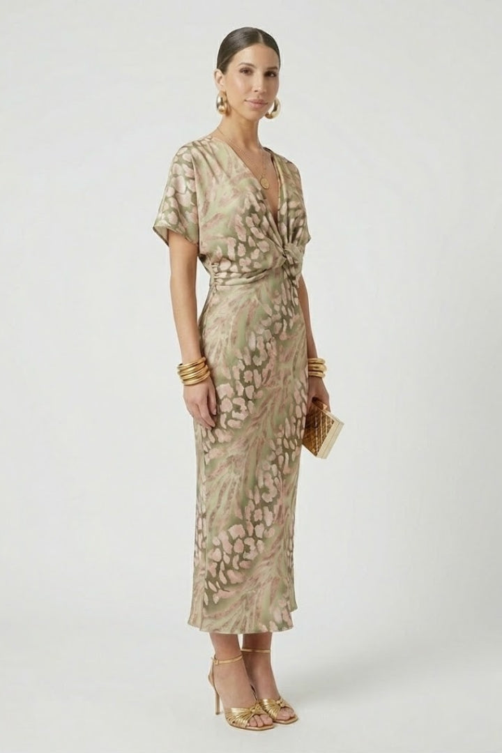 Side angle woman showing V-neck pleated dress on plain background