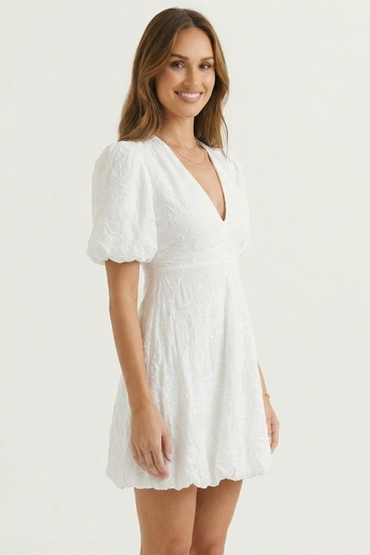 Woman in bubble hem dress standing against plain gray background.