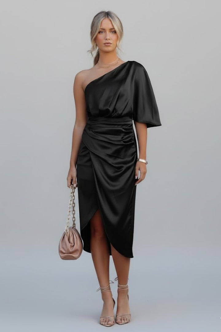 Female model highlighting side slit dress on plain gray background.