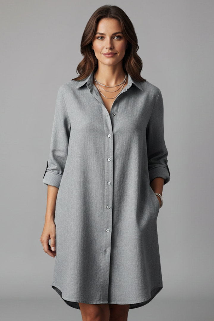  Female model showcasing a collared long sleeve dress with side pockets on a plain background.