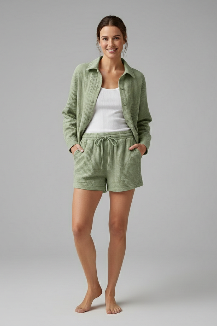 Woman adjusting collar in relaxed outfit plain gray background