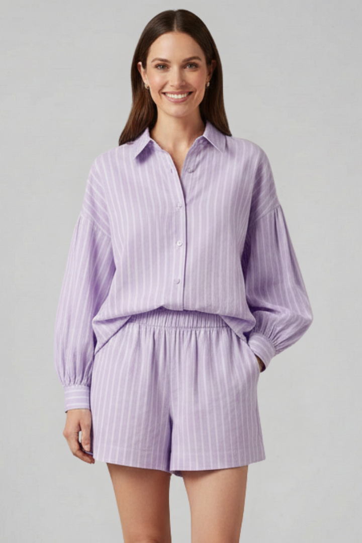 Female model showing side angle of striped outfit, plain gray background.