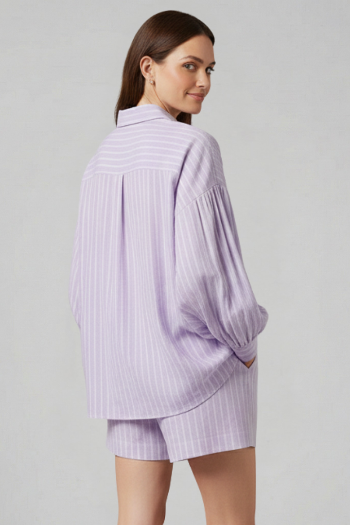 Female model posing back view in striped set, plain gray background.