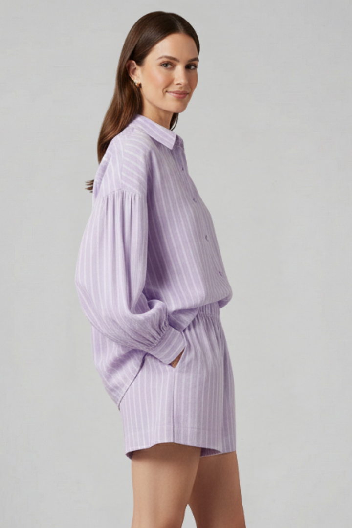 Woman showing button-up striped shirt and shorts, plain gray background.
