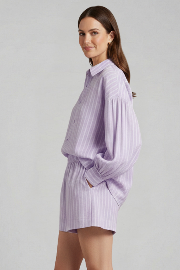 Female model in casual striped co-ord, standing, plain gray background.