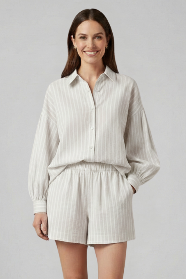 Woman wearing striped two-piece outfit, side pose, plain gray background.
