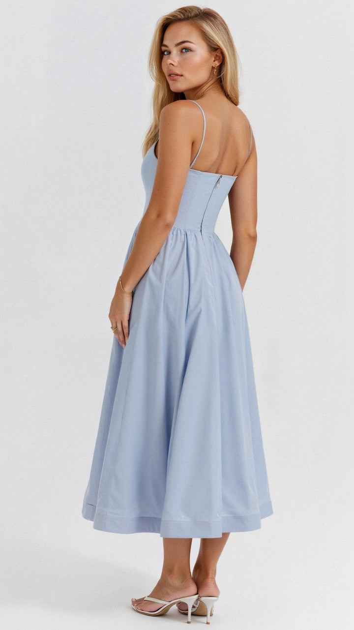 Woman posing in a graceful midi dress featuring a flared skirt and spaghetti straps on a plain background.