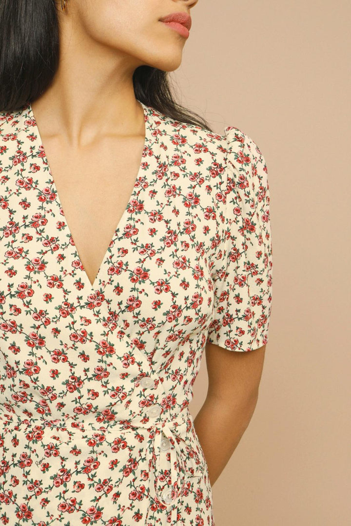 Female model showcasing a floral midi dress with soft drape on a plain background.