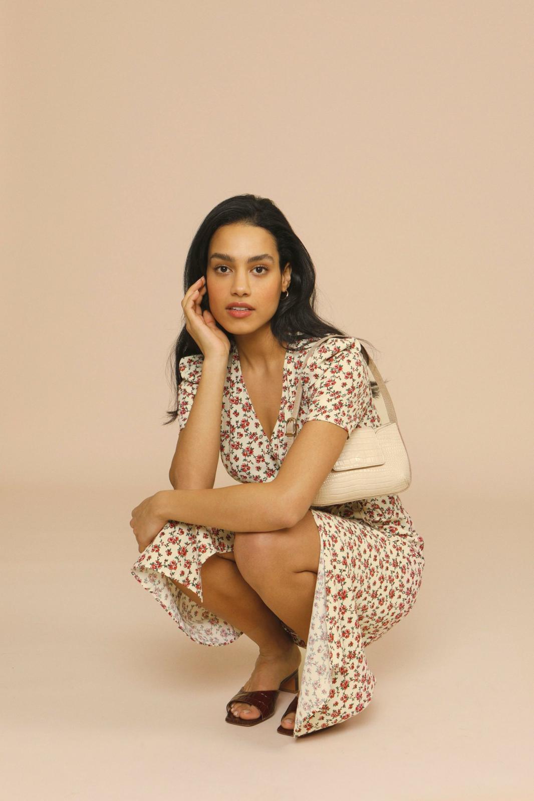 Woman wearing a spring floral midi dress with V-neck on a plain background.