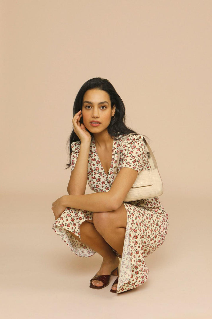 Woman wearing a spring floral midi dress with V-neck on a plain background.