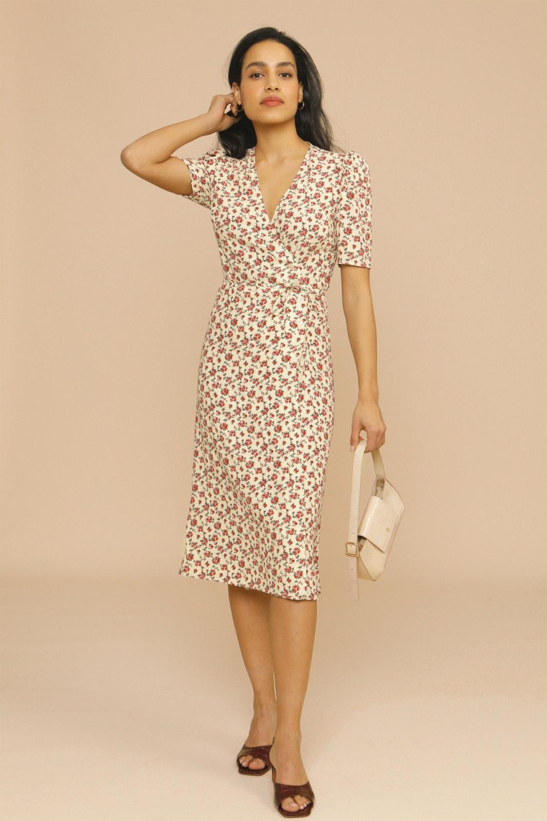 Female model wearing a floral midi dress with V-neck on a plain background.